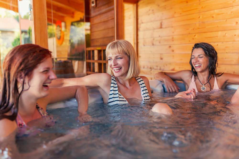 three women sat in a hot tub talking