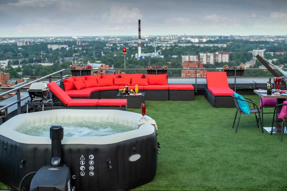 hot tub and corner sofa on fake grass overlooking a city