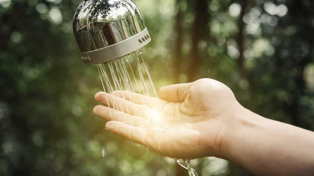 someones hand under a running shower