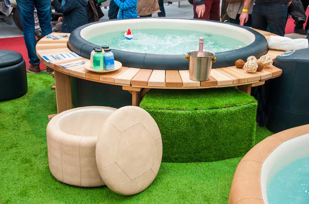 hot tub on fake grass surrounded by people and accessories