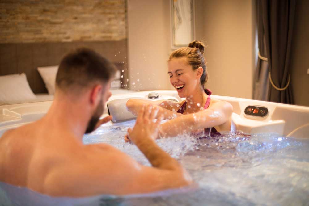 a couple splashing eachother in a hot tub