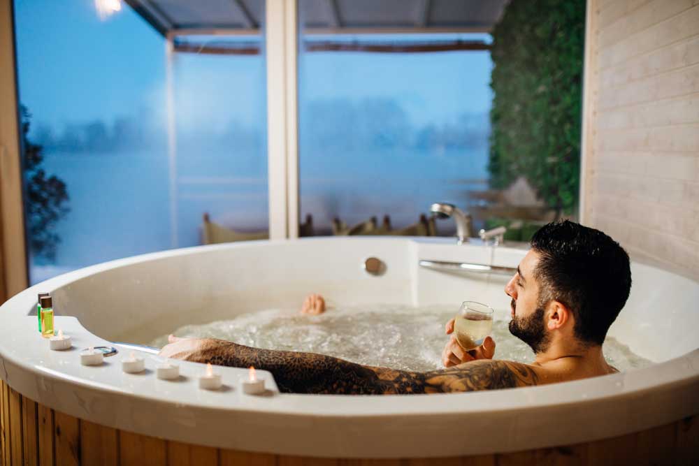 a man sat in a hot tub with a drink