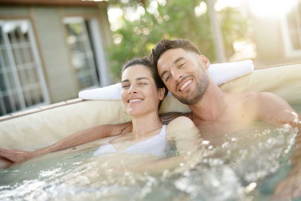 a couple sat in a hot tub smiling