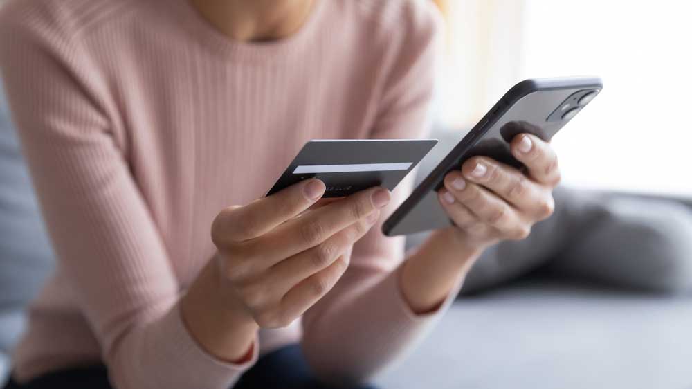 someone holding a phone and credit card next to eachother