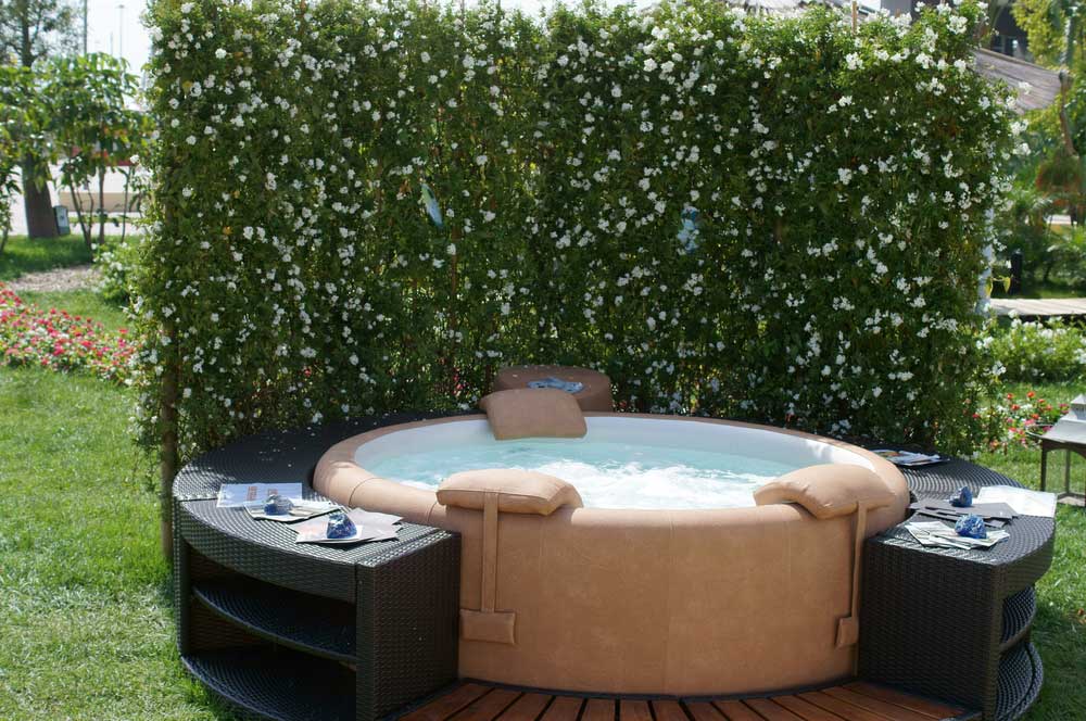 hot tub with seating around it and a bush behind it